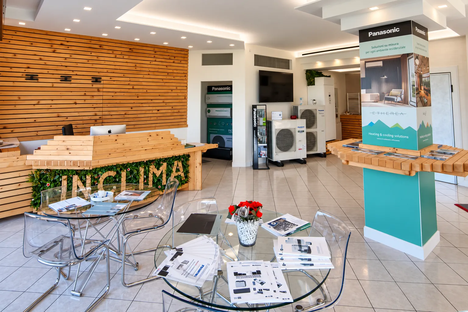 Lo showroom InClima: banco in legno con la scritta IN CLIMA, tavolo con brochure e totem Panasonic